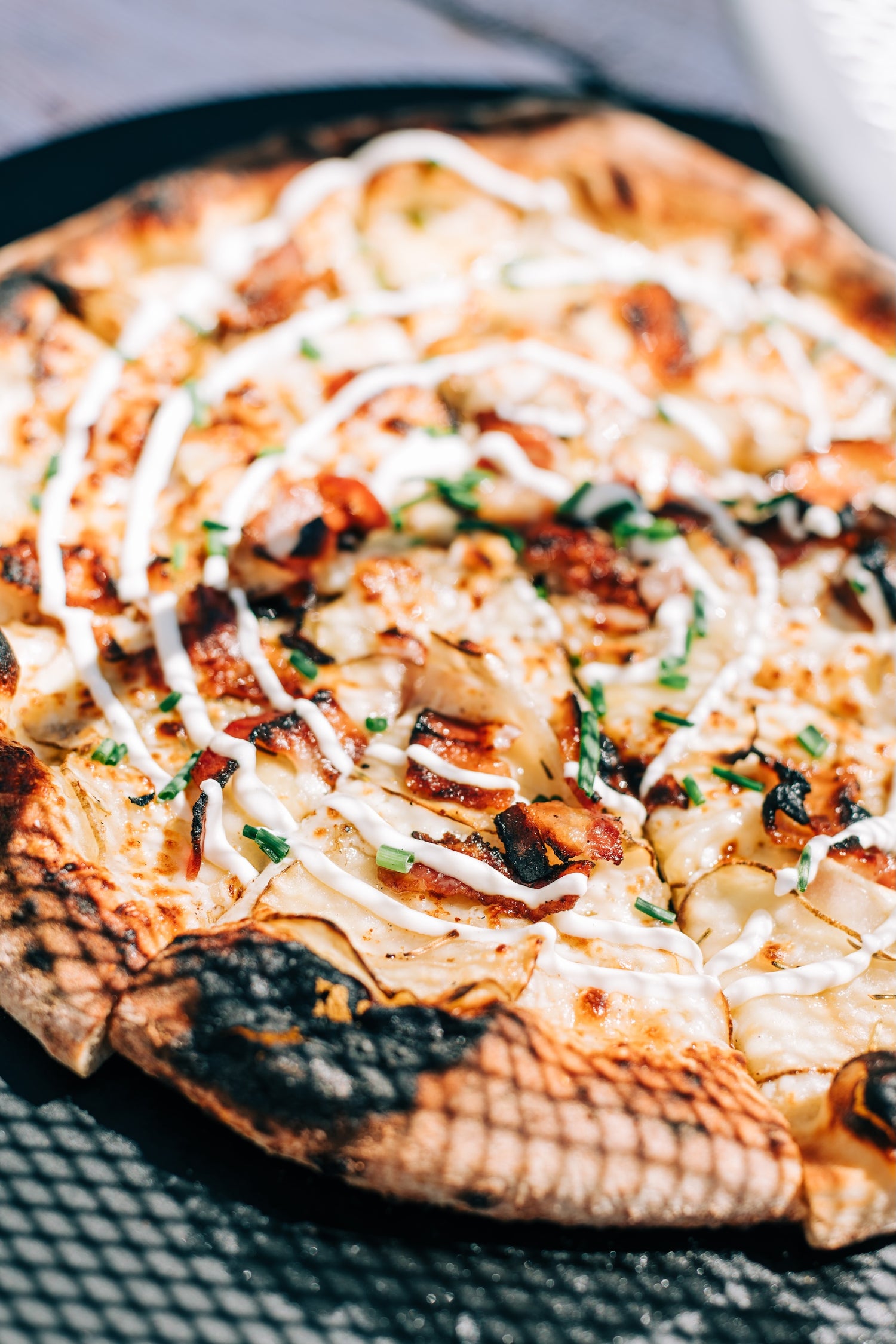 Spud Stud Pizza from Fire & Char - Best Potato Pizza in Richmond & Henrico, VA. Artisan Brick Oven Pizza with Roasted Potatoes, Mozzarella, Caramelized Onions, and Ricotta Cream Drizzle.