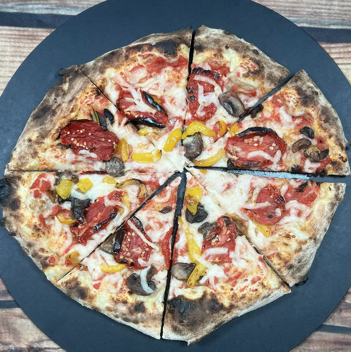 Vegan's Harvest Pizza from Fire & Char - A vibrant, plant-based pizza topped with fresh basil, melty Be-Hive vegan mozzarella, roasted mushrooms, sweet yellow bell peppers, and tangy sun-dried tomatoes. Finished with house-made citrusy lemon oil. Best vegan pizza in Richmond, VA.