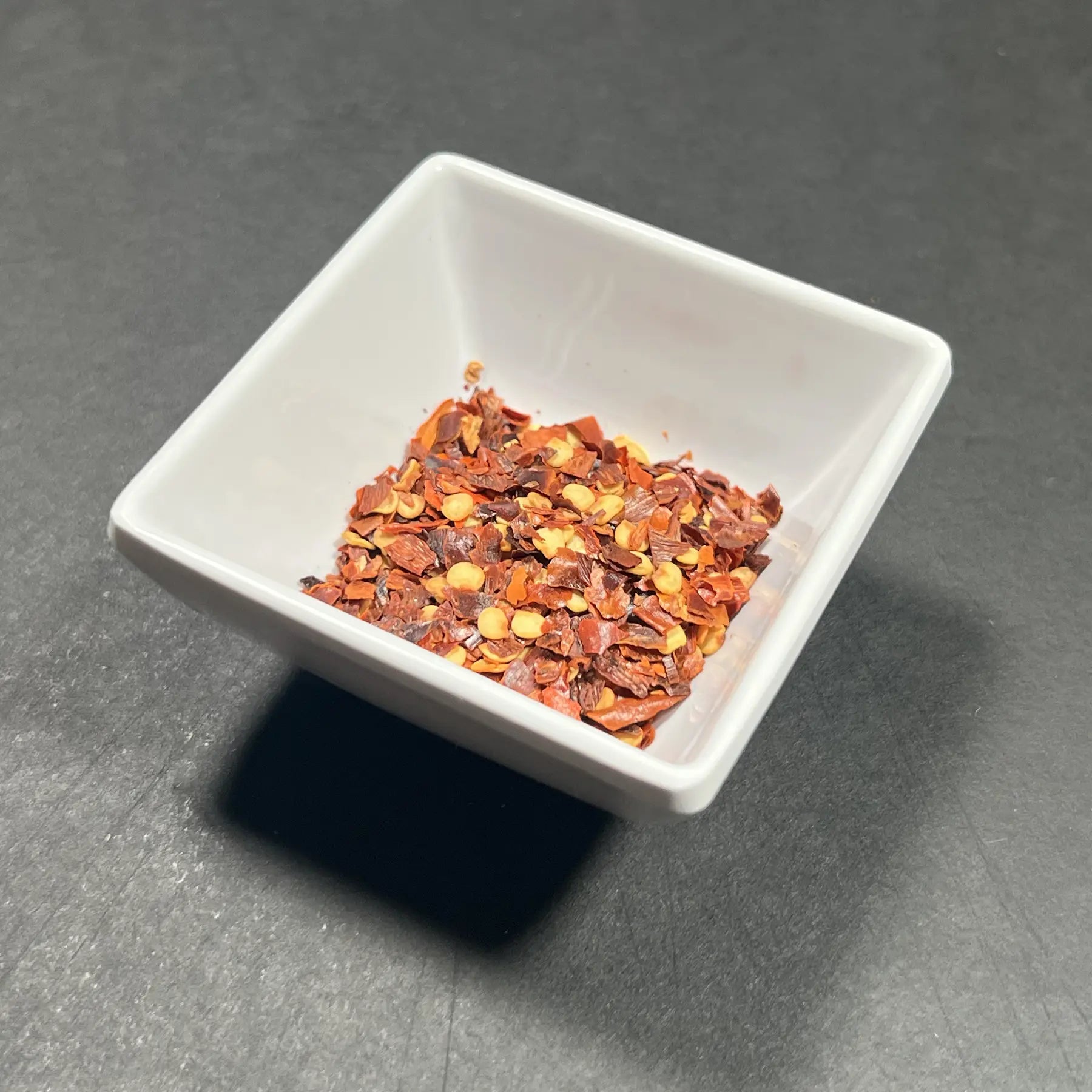 Premium crushed red chili flakes from Fire & Char in Richmond, VA. Perfect for adding a spicy kick to your pizza.